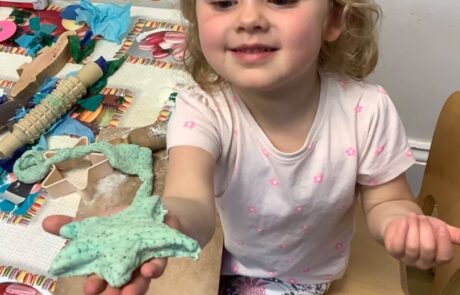 nursery child proud of what she has made from playdoh
