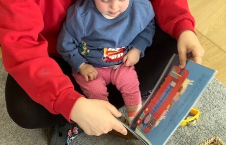 nursery staff reading a book with a baby
